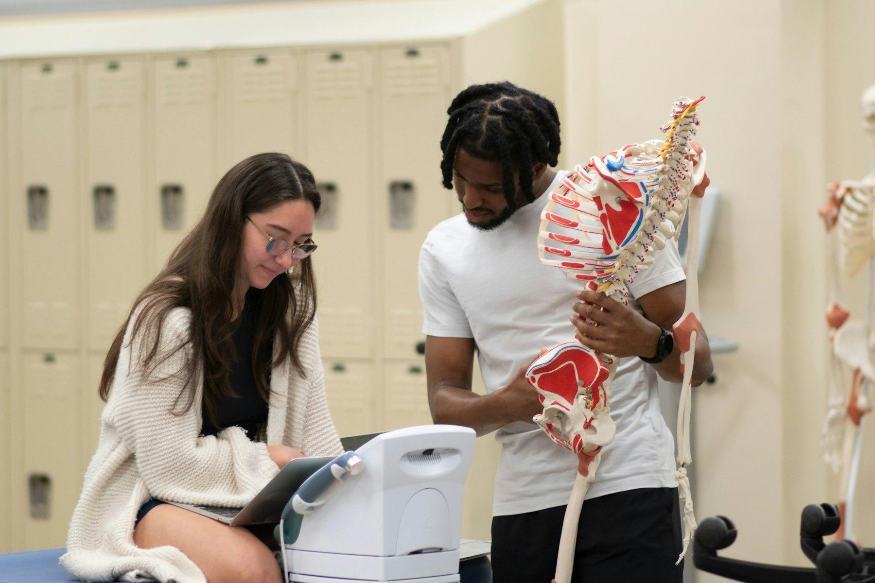 An instructor and a student examining an anatomical model, heads fully in frame